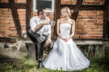 Young couple sitting in front of the old house on a bench clipart