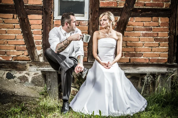 Young couple sitting in front of the old house on a bench — Stock Photo, Image