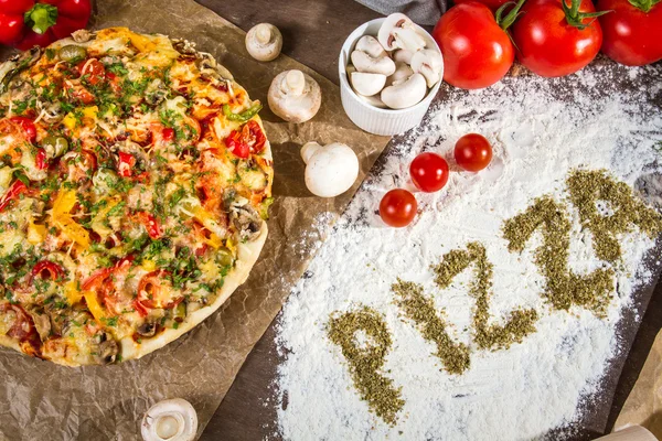 Orden "pizza" skrivet på mjölet med kryddor oregano — Stockfoto