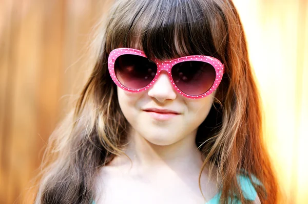 Gros plan portrait d'une enfant fille en lunettes de soleil roses — Photo