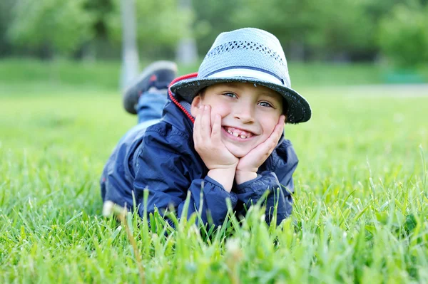 Portret chłopca leżącego na zielonej trawie — Zdjęcie stockowe