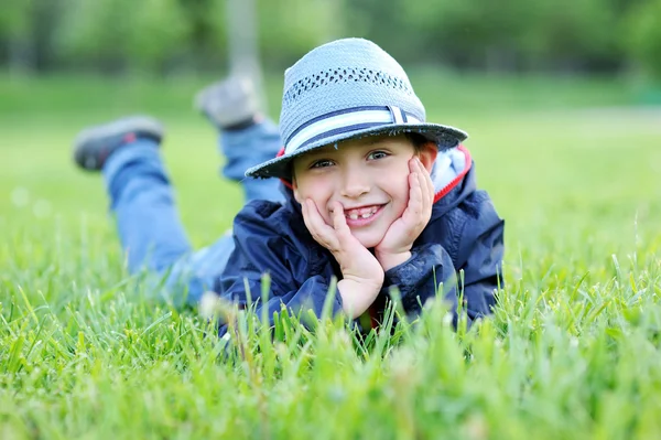 Portrét chlapce leží na zelené trávě — Stock fotografie