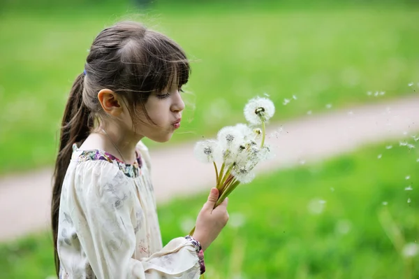 Child girl blowing dandelions — Stock Photo, Image
