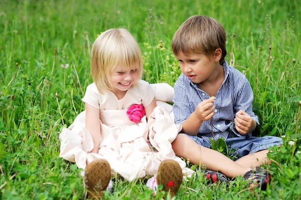 Porträtt av söta barnen sitter på grönt gräs — Stockfoto