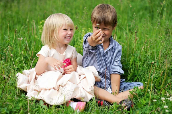 Portrét roztomilé děti sedí na zelené trávě — Stock fotografie