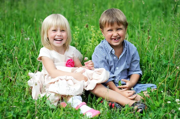 Портрет милых детей, сидящих на зеленой траве — стоковое фото
