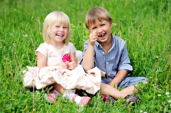 Portret ładny dzieci siedzi na zielonej trawie — Zdjęcie stockowe