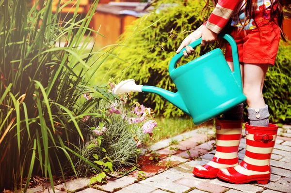 Маленькая девочка в саду с зеленой банкой полива — стоковое фото