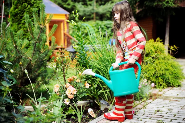 Little girl in a garden with green watering can — Stock Photo, Image