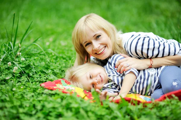 Jonge moeder en dochter liggen op gras — Stockfoto