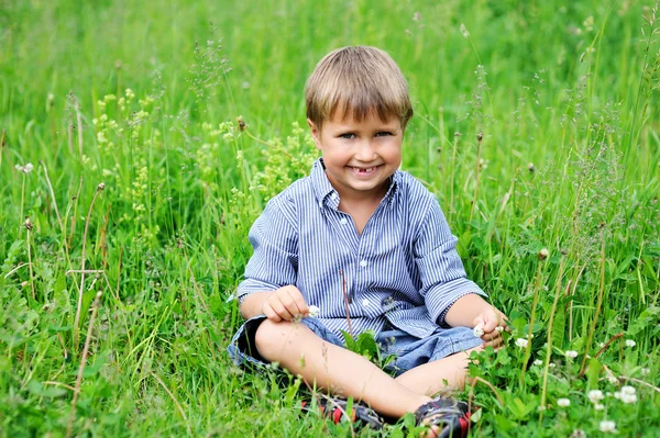Retrato de menino bonito sentado na grama verde — Fotografia de Stock