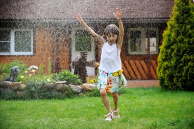 Little girl refreshing herself in a garden clipart