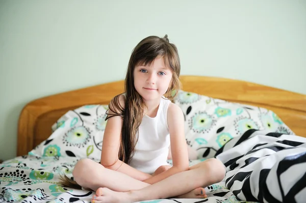 Porträt eines kleinen Mädchens, das im Bett sitzt — Stockfoto