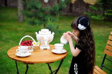 Elegant child girl having a tea party outdoors clipart