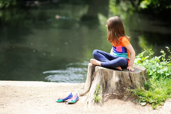 Kleines Mädchen sitzt auf Baumstumpf — Stockfoto