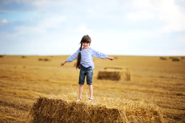 站在顶部的大草堆上的小女孩 — 图库照片