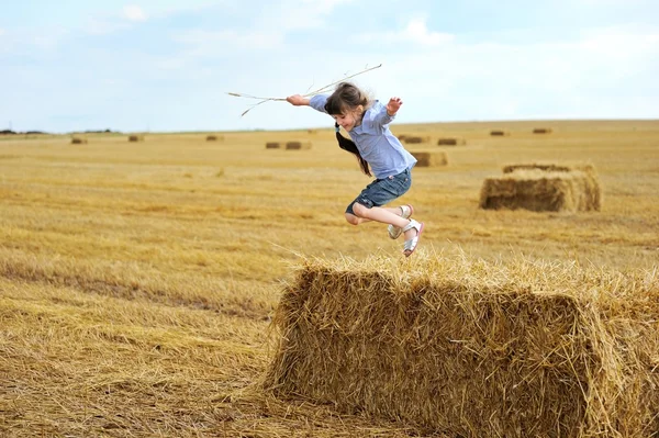 Little girl jumping from a top of haystack — Stock Photo, Image