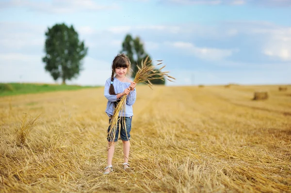 Kleines Mädchen mit einem Bündel Weizenstacheln — Stockfoto