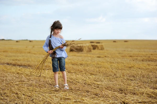 Kleines Mädchen mit einem Bündel Weizenähren — Stockfoto