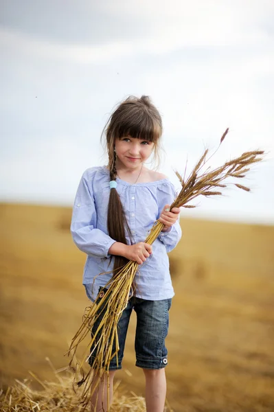 Niña sosteniendo racimo de espigas de trigo — Foto de Stock