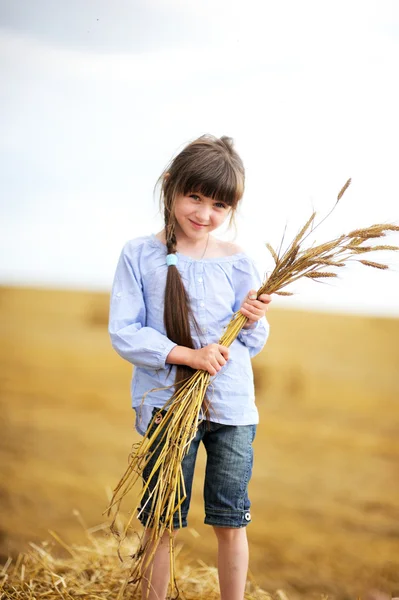 Niña sosteniendo racimo de espigas de trigo — Foto de Stock