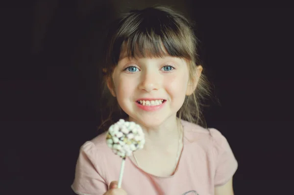 Grappige kind meisje tonen een marshmallow cake — Stockfoto