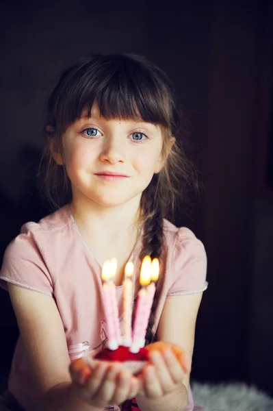 Barn flicka håller en cupcake med fem ljus — Stockfoto