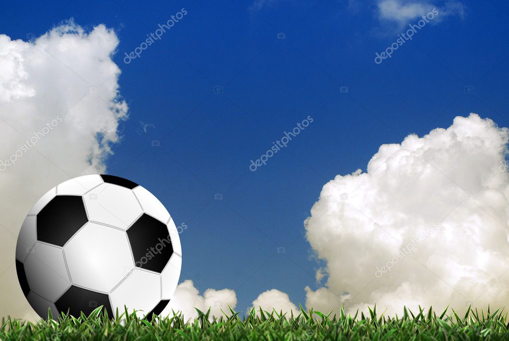 Football in green grass with cloud background