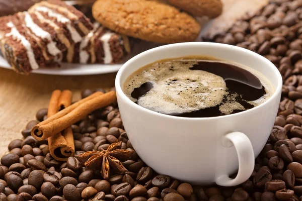 Coffee cup, sweets, cinnamon, anise on coffee beans — Stock Photo, Image