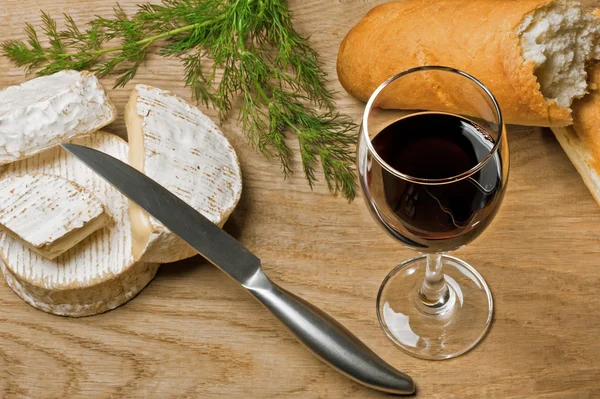 Vino rosso, formaggi Brie e Camembert con pane in tavola — Foto Stock