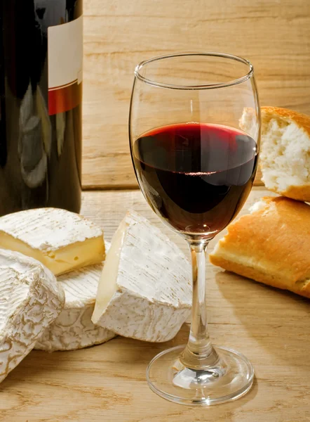 Červené víno, brie, camembert a chléb na stůl — Stock fotografie