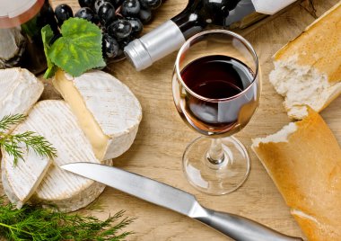 Red wine, Brie and Camembert cheeses with bread on the table clipart