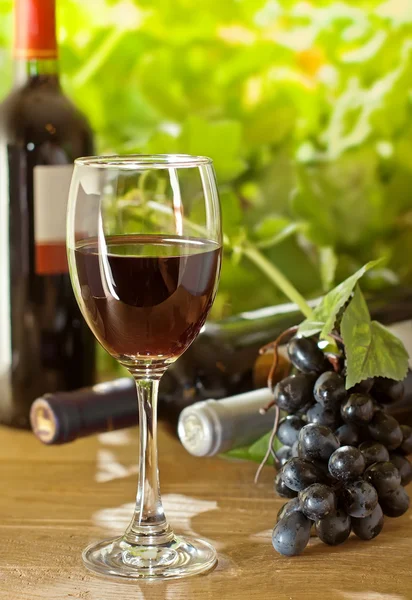 Vin rouge et raisin sur la table en bois — Photo
