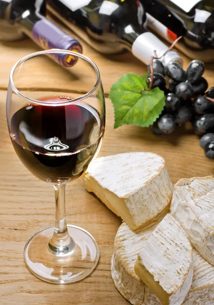 Czerwone wino, brie, camembert i winogron na stół z drewna — Zdjęcie stockowe