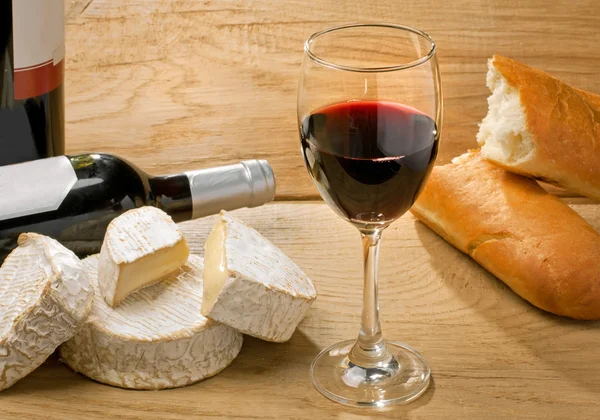 Красное вино, бри, камамбер и хлеб на столе — стоковое фото
