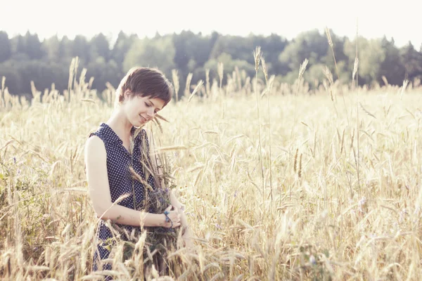 Dívka v modrých šatech obejmout náručí pšenice — Stock fotografie