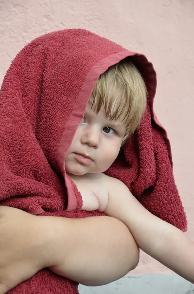 stock image The baby in a red towel at mother on hands.