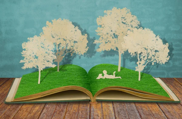A redução de papel de crianças lê um livro abaixo da árvore no velho livro — Fotografia de Stock