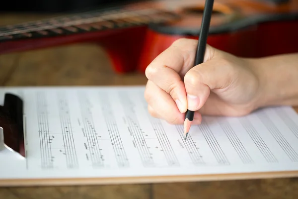 Hand with pencil and music sheet — Stock Photo, Image