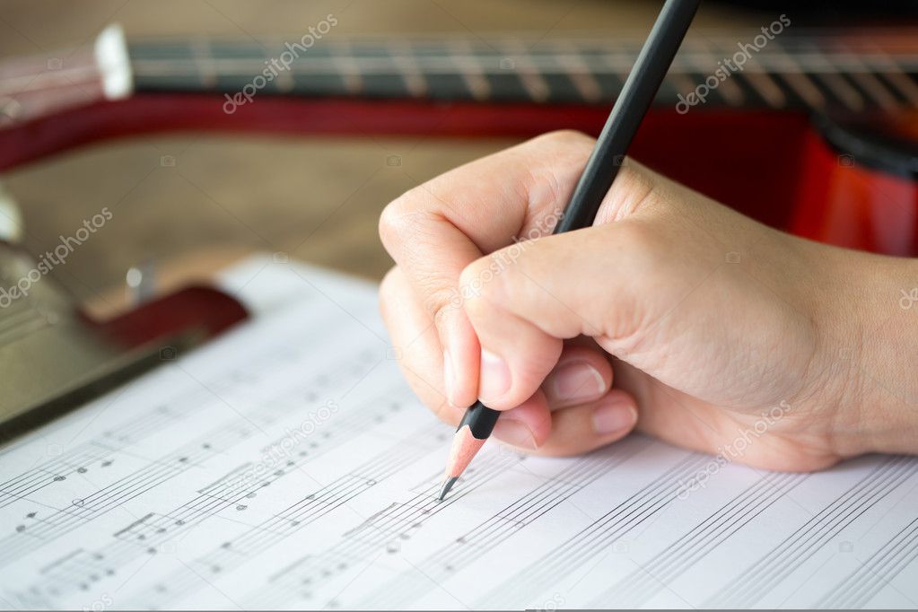 Hand with pencil and music sheet
