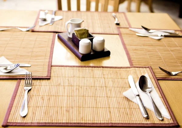 Nomeações de mesa garfo, faca, colher, guardanapo de seda no tapete de bambu — Fotografia de Stock