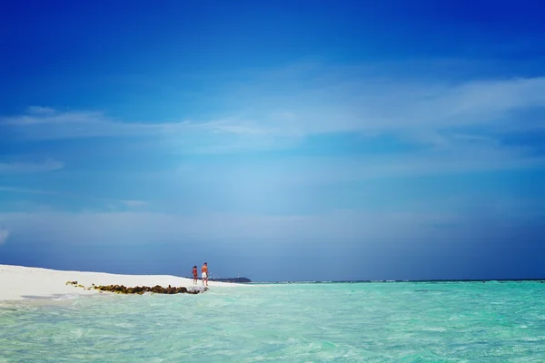 Jovem casal caminhando ao longo da praia do oceano sob o céu azul — Fotografia de Stock