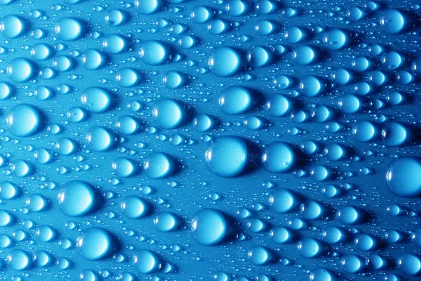 Lesklé vodní kapky na kovově modré povrchu — Stock fotografie