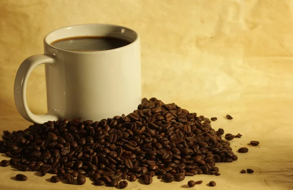 Fincan sıcak kahve kahve çekirdekleri yığını üzerinde — Stok fotoğraf