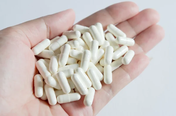 Pílulas brancas na mão — Fotografia de Stock