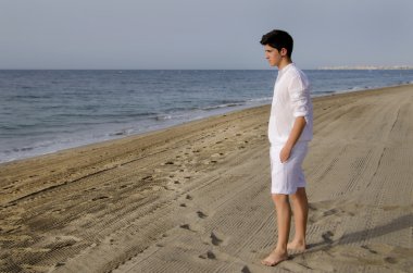 Genç adam sahilde yürüyor.
