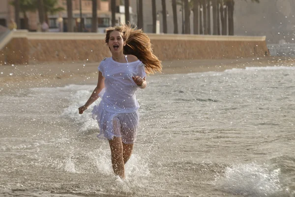 运行在海滩上的年轻快乐的女人 — 图库照片