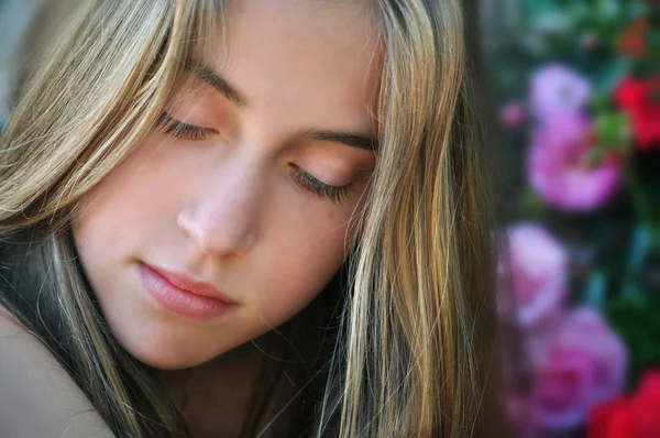 Beautiful teenage girl on a background of flowers — Stock Photo, Image