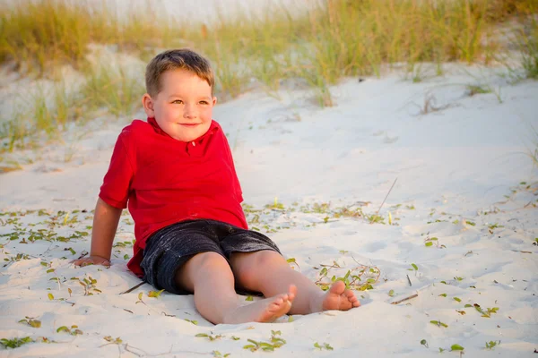 Porträt eines glücklichen Kindes am Strand mit Sanddünen im Hintergrund — Stockfoto