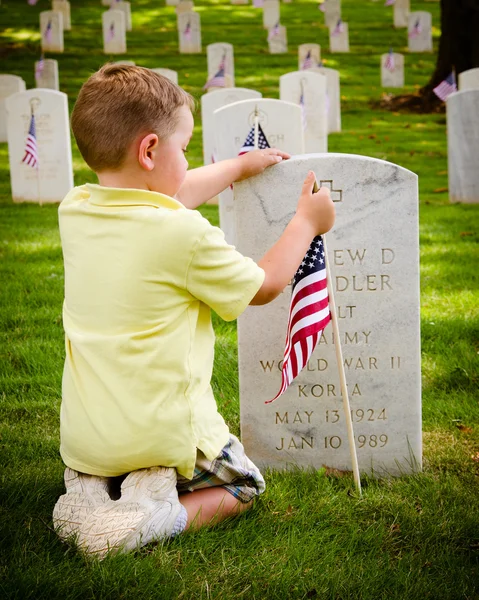 Child straightening a flag at veterans cemetery — Stock Photo, Image